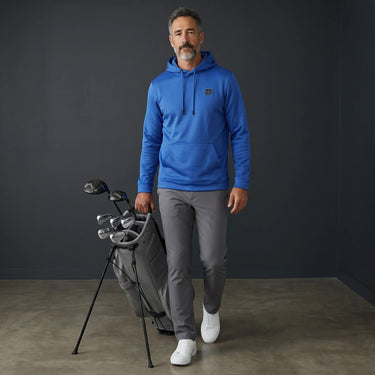 HARG royal blue performance fabric golf hoodie with kangaroo pocket and drawstring hood, worn by a man carrying a golf bag.