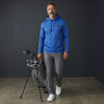 HARG royal blue performance fabric golf hoodie with kangaroo pocket and drawstring hood, worn by a man carrying a golf bag.
