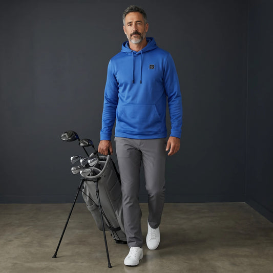 HARG royal blue performance fabric golf hoodie with kangaroo pocket and drawstring hood, worn by a man carrying a golf bag.